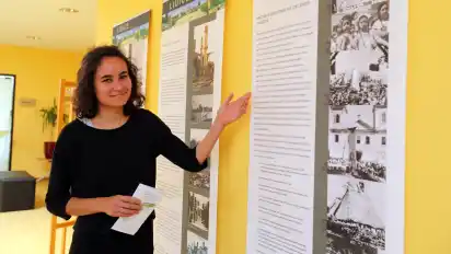 Organisatorin Olan Scott Pinto vom Lidice-Haus zeigt Teile der Ausstellung über die Auslöschung des Dorfes Lidice 1942