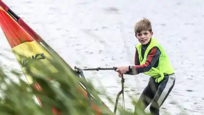 Bloß nicht im Schilf landen – der neunjährige Jaap Holldorf steht auf seinem Surfbrett und steuert vorsichtig Richtung Ufer. Er und seine Familie lernen gemeinsam am Sportparksee Grambke das Windsurfen.