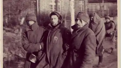 Drei sowjetische Kriegsgefangene stützen sich gegenseitig. Sie sind im Herbst 1941 auf dem Weg ins Stalag X B Sandbostel.