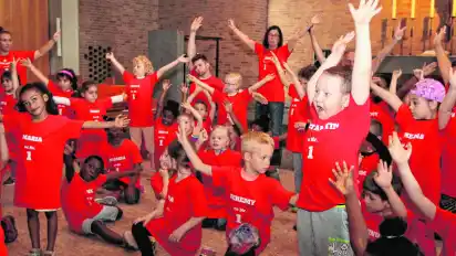 Mit ihren leuchtend roten T-Shirts hängen sich die Kinder mächtig in die Choreografie rein.