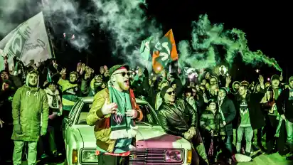 Lässig lehnt Jonny Otten für das Musikvideo am Ford Taunus, Flo Mega rappt vor dem Weserstadion seinen Text.
