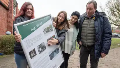 Interessiert blickt Ralf Storjohann (rechts) auf das von den Schülerinnen Vanessa Ehrenberg (von links), Jacqueline Kuhnke und Melisa Kilench erstellte Plakat. Kein Wunder: Schließlich hatten sie sich dafür mit der Historie vom Geschäft August Wilkens auseinandergesetzt, dessen Geschäftsführer Storjohann ist.