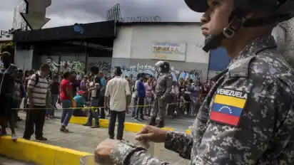 Ein Soldat beobachtet in einer Straße in Caracas Demonstranten.