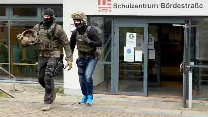 Zwei Beamte des Spezialeinsatzkommandos verlassen das Schulzentrum Bördestraße in Bremen-Lesum.