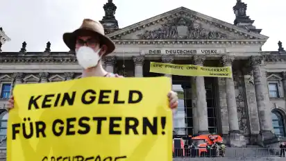 Ein Greenpeace-Aktivist protestiert mit einem Transparent mit der Aufschrift "Kein Geld für gestern" am Reichstagsgebäude für einen schnelleren Kohleausstieg.