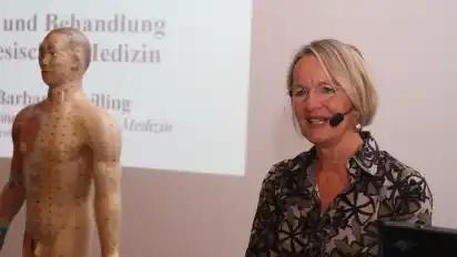Barbara Schilling, ärztliche Leiterin des Instituts für Chinesische Medizin, erklärt die Auswirkungen von Stress auf die Organe. An einer menschlichen Figur und durch eine Fotopräsentation, unter anderem Bilder von unterschiedlichen Stress-Typen, verdeutlicht sie ihre Ausführungen.
