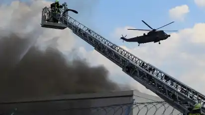 Die Feuerwehr bei den Löscharbeiten. Im Hintergrund ein Hubschrauber der Marine, die Besatzung hatte Hilfe angeboten.