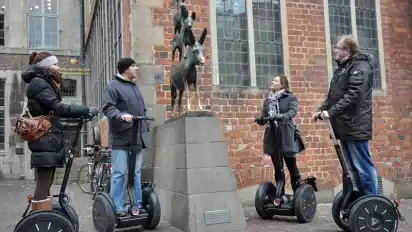 Sightseeing auf dem Segway: Torben Pforr (r) mit einer Gruppe Touristen bei den Bremer Stadtmusikanten. (Foto: Carmen Jaspersen)