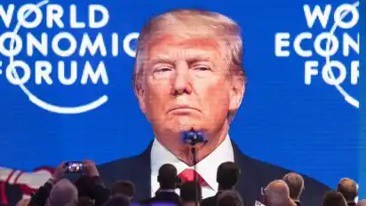 Teilnehmer verfolgen die Übertragung der Rede von US-Präsident Donald Trump auf einem großen Bildschirm in Davos 2018. Foto: Gian Ehrenzeller/KEYSTONE
