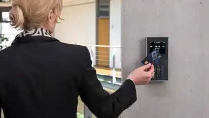 Eine Frau demonstriert mit einer Chipkarte ein modernes Verfahren zur Arbeitszeiterfassung.