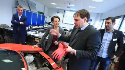 Noch steckt in diesem roten Flitzer ein Verbrennungsmotor. Die Kfz-Azubis für Hochvolttechnik sollen daraus ein E-Auto machen. Stefan Sündermann vom Fraunhofer-Institut zeigt Bildungssenatorin Claudia Bogedan, wie das gehen soll. Links daneben lauscht Kfz-Innungs-Obermeister Hans Jörg Koßmann, der das Projekt mit auf den Weg gebracht hat.