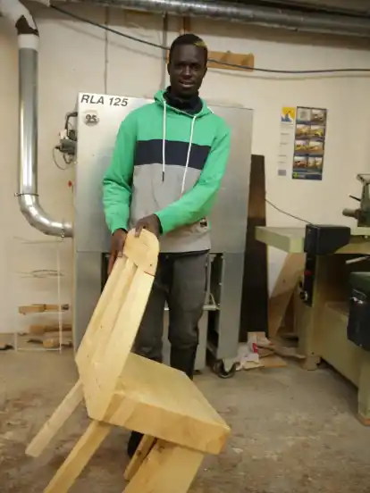 Trainee Kebba Mboge mit dem Stuhl, dessen Design Ideen aus dem ganzen Team vereint.