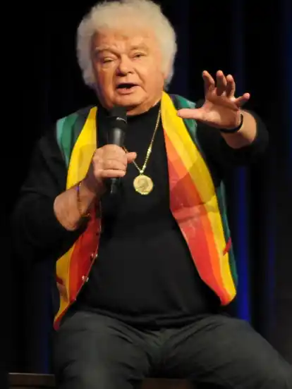 So kennen und lieben ihn seine Fans: Fips Asmussen in Regenbogen-Weste, mit Minipli und dickem goldenen Asmussen-Amulett. Und dann erzählt er drei Stunden lang Witze.