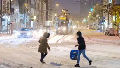 Passanten laufen durch dichten Schnee in der Innenstadt. Das extreme Wetter wirkt sich auch am Dienstag auf den Verkehr in Niedersachsen aus.