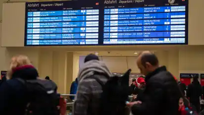Bahnreisende stehen vor einer Anzeigetafel im Hauptbahnhof von Hannover. Mit Orkanböen bis Windstärke 12 hat das Sturmtief "Eberhard" am Sonntag den Bahnverkehr in Teilen Deutschlands zum Erliegen gebracht.