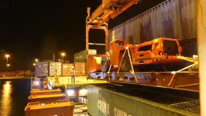 Wenn es in den Spezialrahmen passt, transportiert das Schiff auch Bau-maschinen, die nicht im Container sind. Wo das Gefährt auf dem Schiff seinen Platz findet, hängt ab vom Gewicht der anderen Container, damit für die Fahrt alles möglichst im Gleichgewicht längs und zur Seite austariert ist.