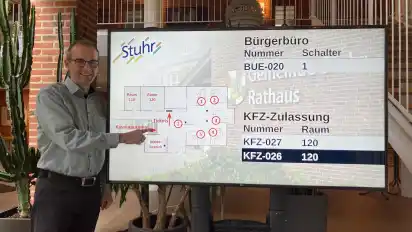 Bürgerbüro-Chef Andreas Leder zeigt den zusätzlichen Wartebereich mit Aufruf-Tafel im Foyer des Stuhrer Rathauses.