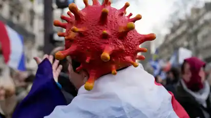 Ein Demonstrant mit einem Virus-Kopfschmuck nimmt an einer Demonstration gegen den neuen Impfpass und die obligatorische Impfung zum Schutz gegen das Coronavirus sowie gegen die anhaltenden staatlichen Beschränkungen teil (Archivfoto).