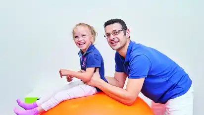 Durch Krankengymnastik kann Yaroslav Prannyk diesem Mädchen mit der Diagnose Infantile Cerebralparese in der neurologischen Rehabilitation im Therapiezentrum Spaß an Bewegung vermitteln.