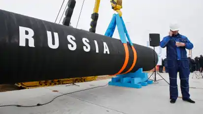 2010 in Russland, Portowaja: Ein russischer Bauarbeiter steht neben einem Rohrstück für die Pipeline. Nord Stream 1 transportiert seit 2011 Gas vom russischen Wyborg auf dem Grund des Meeres bis ins deutsche Lubmin bei Greifswald in Mecklenburg-Vorpommern.