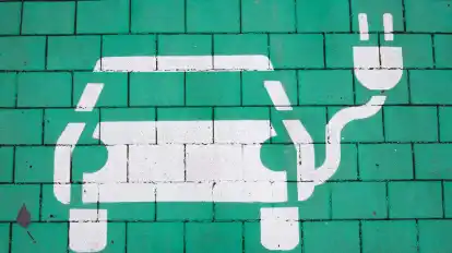 Ein Elektroauto auf grünem Grund markiert einen Parkplatz für Elektrofahrzeuge.