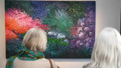 Zwei Besucherinnen schauen sich das Bild "Garten bei Nacht" aus 2010 von Ansgar Skiba an.