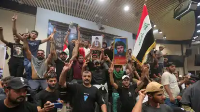 Irakische Demonstranten posieren mit Nationalflaggen und Bildern des schiitischen Geistlichen Al-Sadr vor dem Parlamentsgebäude.