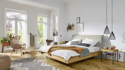 Möbel aus Holz zusammen mit weißen und pastellfarbenen Dekoelementen sorgt für Wärme, wie hier im Schlafzimmer.