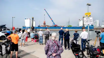 Dutzende Schaulustige wollten sich am Freitag diesen Anblick nicht entgehen lassen: Ein Kran ist dabei, die Kuppel vom schiefen Leuchtturm auf der Nordmole abzunehmen.