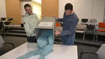 Jannik Ewald (links) und Patrick Lorenz vom Briefwahlvorstand Grasberg II öffnen um Punkt 18 Uhr im Osterholzer Kreishaus die Urne mit einem Teil der Stimmzettelumschläge, die per Briefwahl aus der Wörpe-Kommune eingetroffen sind.