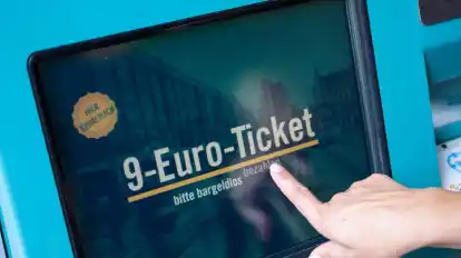 Eine Frau zieht sich an einem Fahrschein-Automaten ein 9-Euro-Ticket.