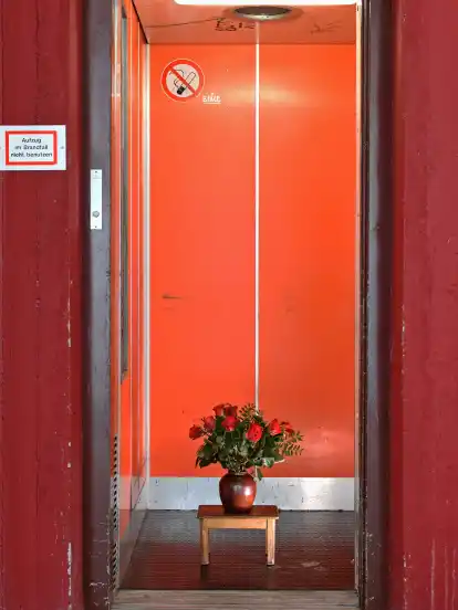 Hinter einer unscheinbaren, roten Tür verbirgt sich ein Blumenstrauß.