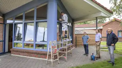 Die Fensterrahmen des Kindergartens bekommen einen neuen Anstrich, beobachtet von Henning Arera (unten von rechts), Andreas Brandt und Bernd Roseland.