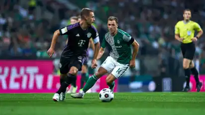 Senne Lynen (SV Werder Bremen #14), rechts, läuft Joshua Kimmich (FC Bayern München #6), im Vordergrund am Ball, an.