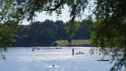 Menschen paddeln in der Sonne auf dem Hamburger Stadtparksee.