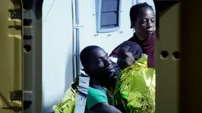 Gerettete Migranten gehen auf der italienischen Insel Lampedusa von einem Boot an Land.