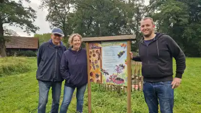 Stecken viel ehrenamtliches Engagement in Hurrels Blühwiese: Manfred Köster (von links), Heike Köster und Jannis Köster vor einem Schild des neuen Wildbienenpfads.
