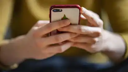 Ein Jugendlicher hält ein Smartphone in seinen Händen (Symbolbild)