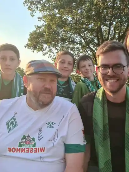 Die jugendliche Vorstandsvorsitzende Emily Münch (links) und Kassenwart Stefan Münch (rechts) von „Fischkopp deLux“ mit Mitgliedern des Werder-Bremen-Fan-Clubs bei einem Heimspiel vor dem Weserstadion.