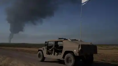 Israelische Soldaten in der Nähe der Grenze zwischen Israel und dem Gazastreifen, während in dem Küstengebiet Rauch in den Himmel steigt.