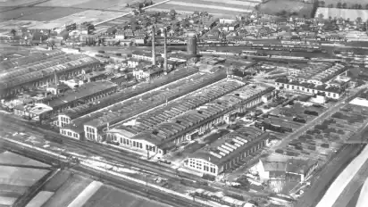 Das Ausbesserungswerk 1936 mit Wasserturm und der Eisenbahnersiedlung im Hintergrund.