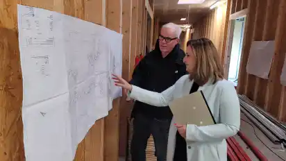 Dirk de Jong und Irina Lindemann schauen sich beim Besuch der Baustelle einen Plan an. Sie befinden sich im Flur der neuen Einrichtung.