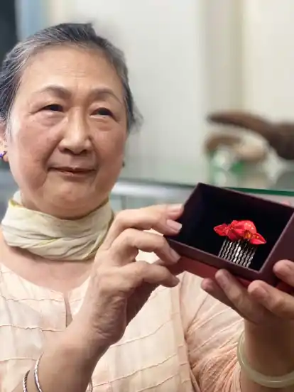 Meisterin Cheng fertigt Wickelblumen, hier ein traditioneller Brautschmuck.