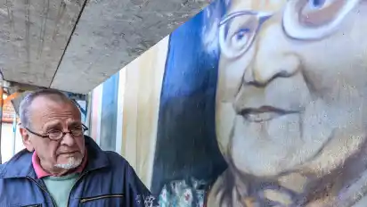 Peter K. F. Krueger 2021 bei der Restaurierung seines damals 46 Jahre alten Wandbildes ”Blick aus dem Fenster” (Oma und Opa) an der Hauswand der Awo.