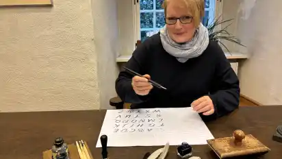 Karin Tausendfreund bietet am Tag des offenen Denkmals an einem Mitmachstand Schreiben mit der Feder an.