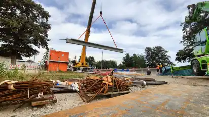 Die Betonbinder für die neue Wörpebrücke hängen am Haken des Schwerlastkrans.