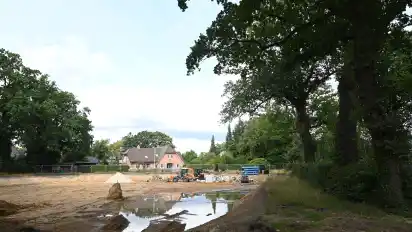 Das neue Regenrückhaltebecken am Ortseingang von Platjenwerbe. Sorgen bereitet einigen Bürgern, dass die Kronentraufe der Eichen beim Bau unterschritten worden ist, wie die Äste zeigen, die nun über das ausgehobene Becken ragen.